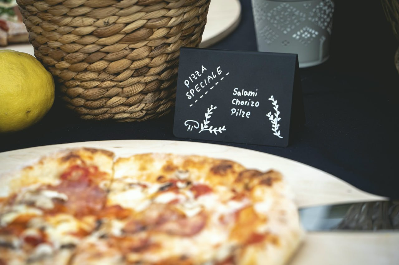 Pizza-Station mit Kreideschild Pizza Speciale bei einer Veranstaltung