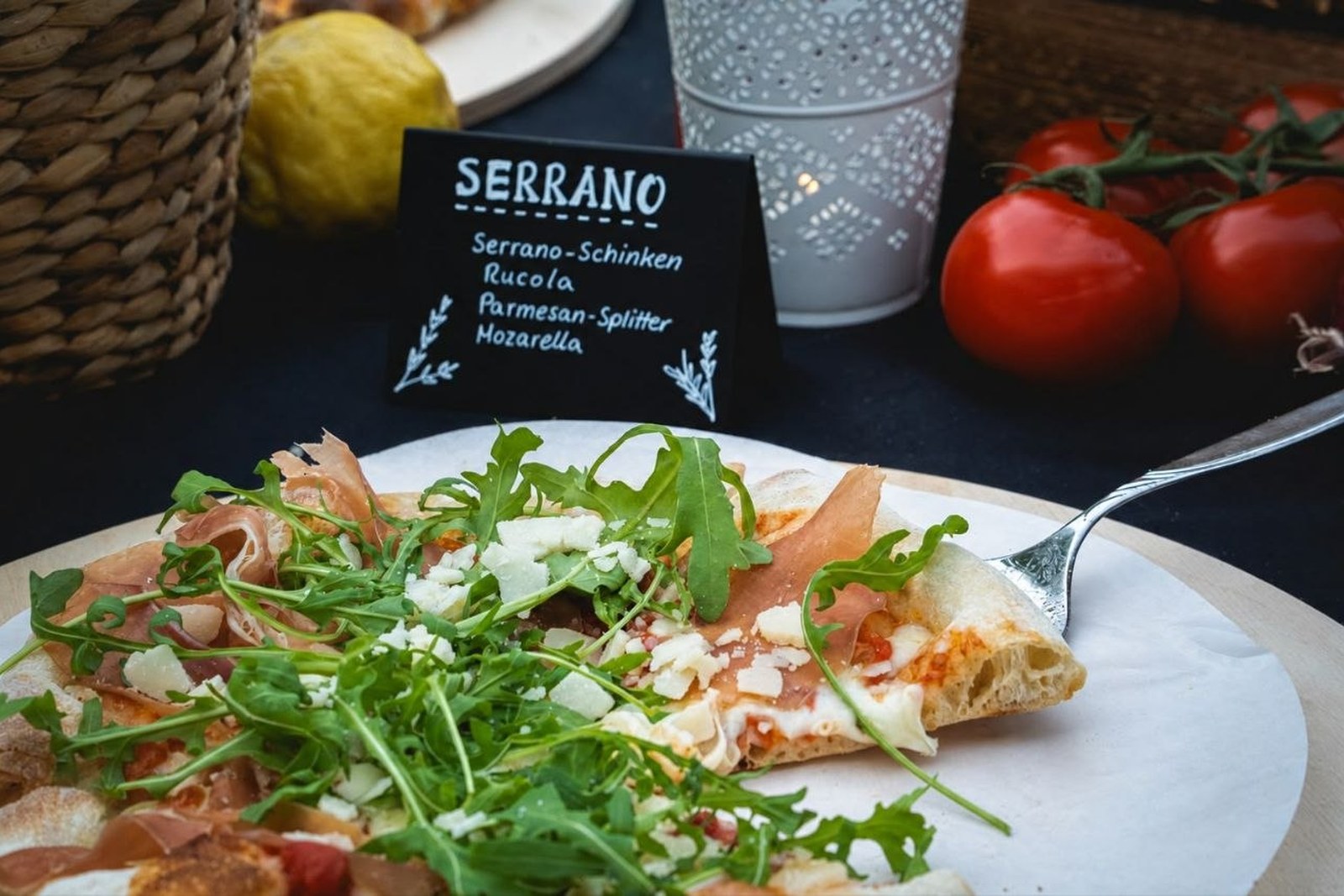 Pizza Serrano mit Serranoschinken, Rucola und Parmesan auf Holzbrett