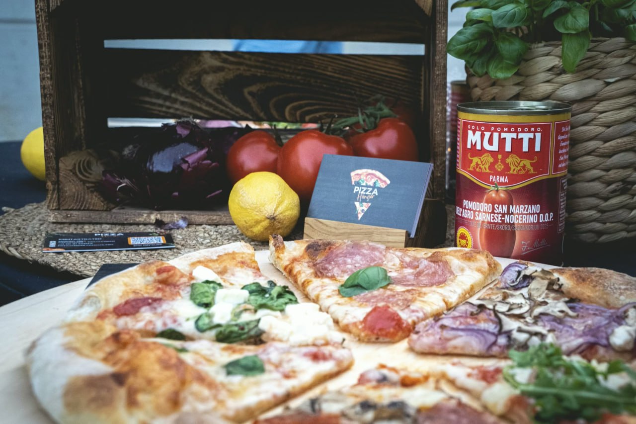 Mutti San Marzano Tomaten, frisches Basilikum und Pizzascheiben auf Holzbrett